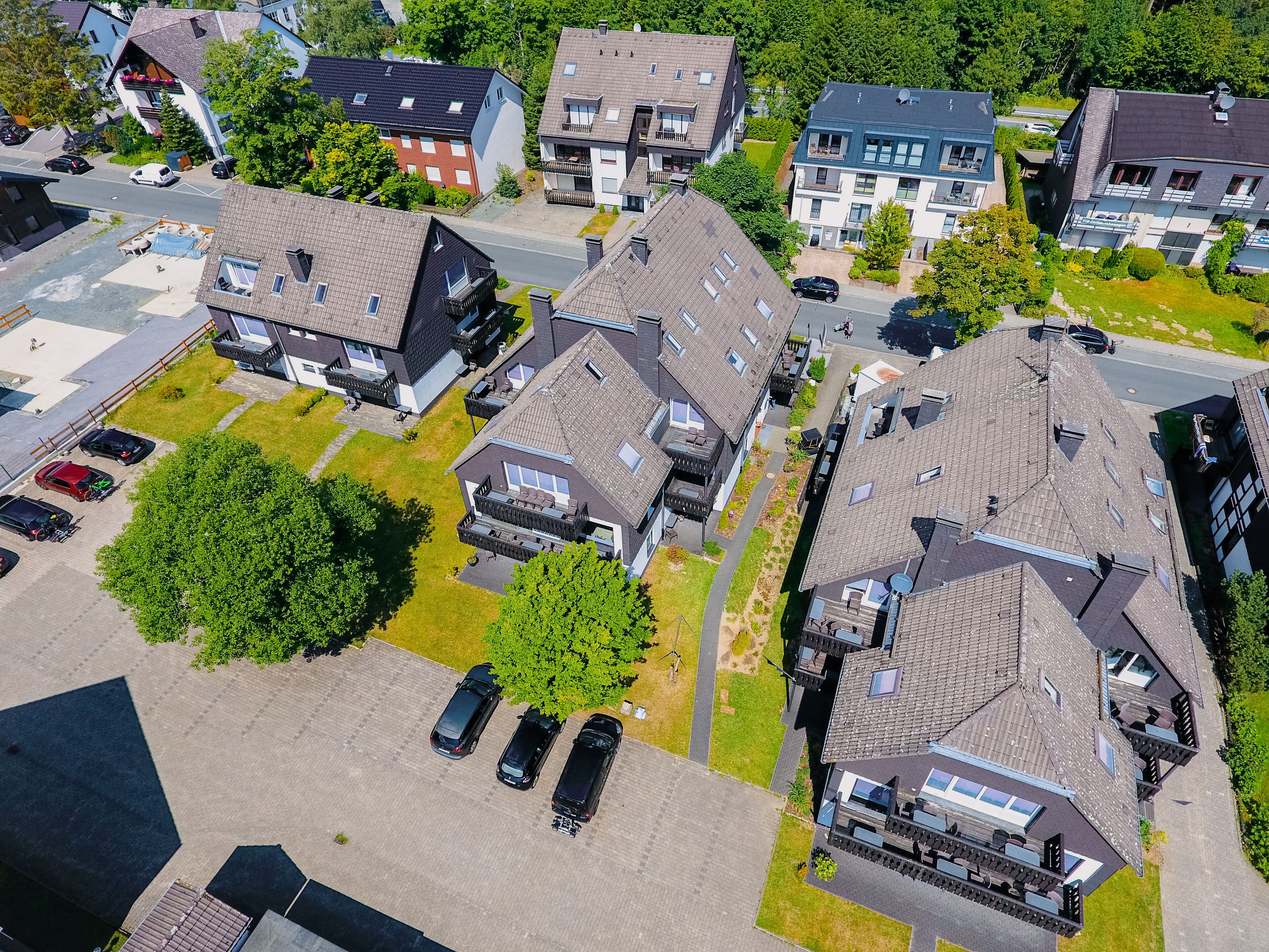 An aerial view of a residential area with multiple houses, a parking lot, and a small green space.