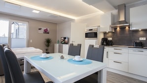 A modern hotel room with a dining area, kitchenette, and a bed. - Ferienpark Winterberg (Winterberg)
