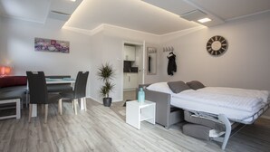 A modern, well-lit room with a bed, seating area, and a small kitchenette. - Ferienpark Winterberg (Winterberg)