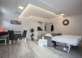 Una habitación moderna y bien iluminada con cama, zona de estar y una pequeña kitchenette.