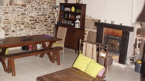 Ein rustikales Wohnzimmer mit Steinwand, Holzmöbeln, Kamin und einer Sitzbank auf Rollen.