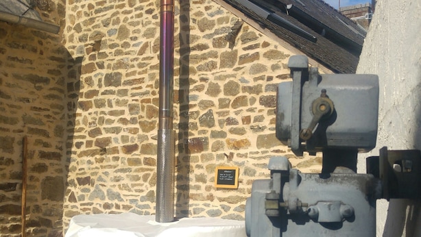 Ein Steinhaus mit Holzbadefass, einer Metallleiter und einem Warmwasserbereiter.