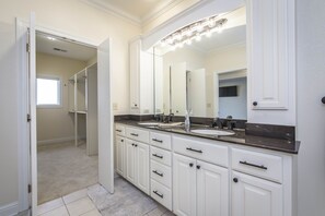 A bathroom with a large mirror, two sinks, and a walk-in closet. - Breathtaking Lakeview Home in Diamond Bluff (Quitman)