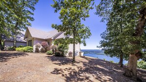 Une maison avec un toit en pente, entourée d’arbres et offrant une vue sur un lac.