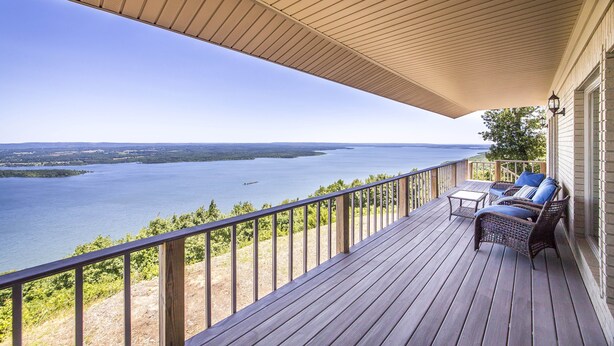 Une terrasse en bois offrant une vue sur un lac et sur la terre ferme au loin.