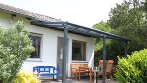 Un espace patio doté d’un coin salon abrité, d’une petite table et d’une nichoir fixé au mur.