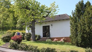 Une petite maison de plain-pied avec une porte noire et des marches menant à un porche avant.