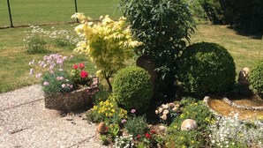 Un jardin agrémenté de diverses plantes et fleurs, un sentier en pierre et une vue sur des collines lointaines.