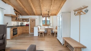 Une cuisine spacieuse avec des meubles en bois, un coin repas avec un banc et une vue sur l’extérieur.