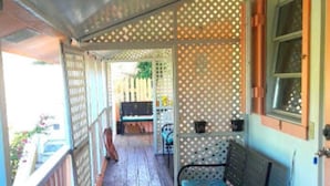 A covered porch with a wooden floor, a bench, and a chair. - "We Make Your Stay In The Bahamas Both Comfortable and Affordable" (Governors Harbour)