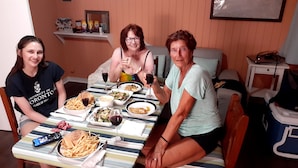 Three people seated at a dining table with various dishes and drinks. - "We Make Your Stay In The Bahamas Both Comfortable and Affordable" (Governors Harbour)