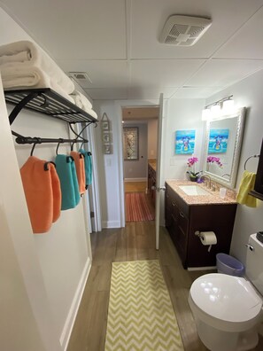 Une salle de bain avec un lavabo, des toilettes et un miroir. On y trouve un porte-serviettes avec plusieurs serviettes.