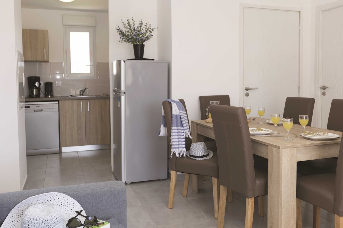 Una cocina compacta con refrigerador, cafetera y comedor con mesa lista para dos.