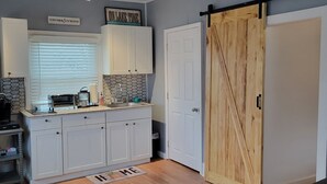 Een moderne keuken met witte kasten, een houten schuifdeur en een backsplash van visgraatmozaïek.