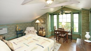 A bedroom with a bed, a desk, a chair, a lamp, and a window. - Romantic, 1 bedroom cottage walking distance to downtown, pet friendly, private. (Eureka Springs)