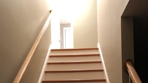 A wooden staircase with white handrails and a light source at the top. - Immaculate Cape Cod Family Retreat- minutes from Ponds, Lakes, and Ocean! (Sandwich)