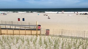 A beach with a wooden fence, a lifeguard tower, and people relaxing.