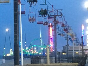 A Ferris wheel with cabins, a roller coaster, and a brightly lit amusement park at dusk. - Beautiful Ocean Terrace Beach House with High-Speed Internet at North End (Seaside Heights)
