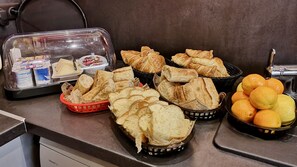 A breakfast buffet with bread, pastries, and oranges. - L'etap'corteline (Saint-Remy)