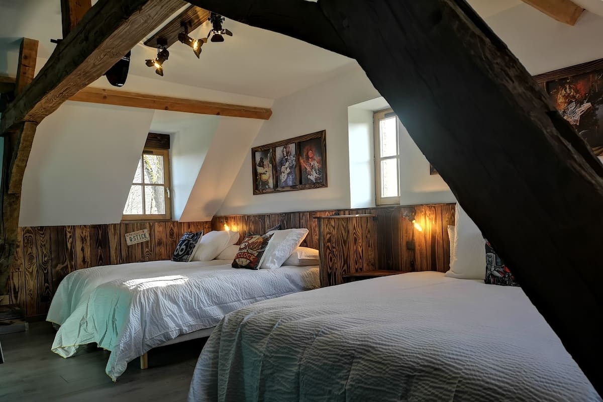 Ein Schlafzimmer mit zwei Betten, einem Holzkopfende und einer schrägen Decke.