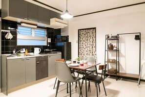 A modern kitchen with dark cabinetry, a central island, and a dining area with chairs and a table. - Il sole Kujo 501 (Osaka)