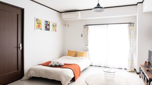 Un dormitorio con cama, alfombra redonda, televisor y una puerta.