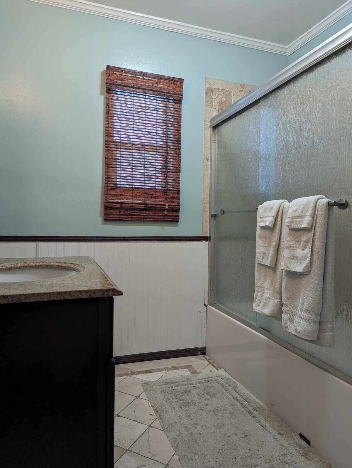 A bathroom with a window, a shower, and a sink.