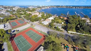 Vue aérienne d’une zone côtière comprenant des courts de tennis, des immeubles résidentiels et un port de plaisance.