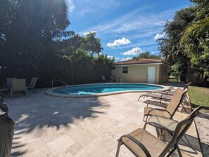 A swimming pool with a curved edge, surrounded by lounge chairs and a small building in the background. - 3/2 Heated Private Pool, 5 Min to Beach (Lantana)