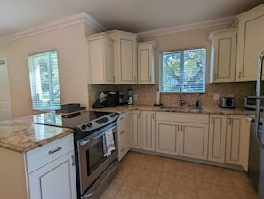 A kitchen with white cabinets, a granite countertop, a stove, and a refrigerator. - 3/2 Heated Private Pool, 5 Min to Beach (Lantana)