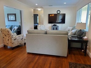 A living room with a sofa, armchair, TV, and a lamp. - 3/2 Heated Private Pool, 5 Min to Beach (Lantana)