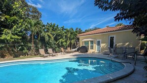 A swimming pool with a tiled deck, surrounded by lounge chairs and a covered seating area. - 3/2 Heated Private Pool, 5 Min to Beach (Lantana)