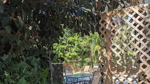 A patio area with a pool table, chairs, and a wooden lattice fence. - 3/2 Heated Private Pool, 5 Min to Beach (Lantana)