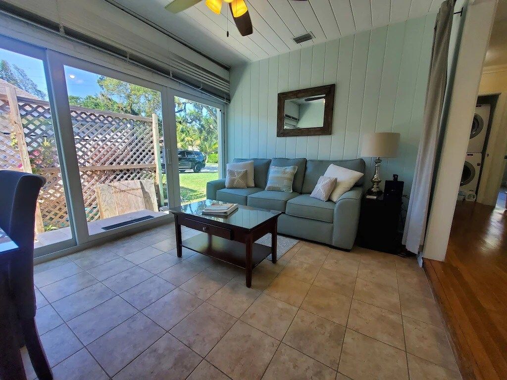 Ein Wohnzimmer mit einer Couch, einem Couchtisch und einer Schiebetür, die auf eine Terrasse führt.