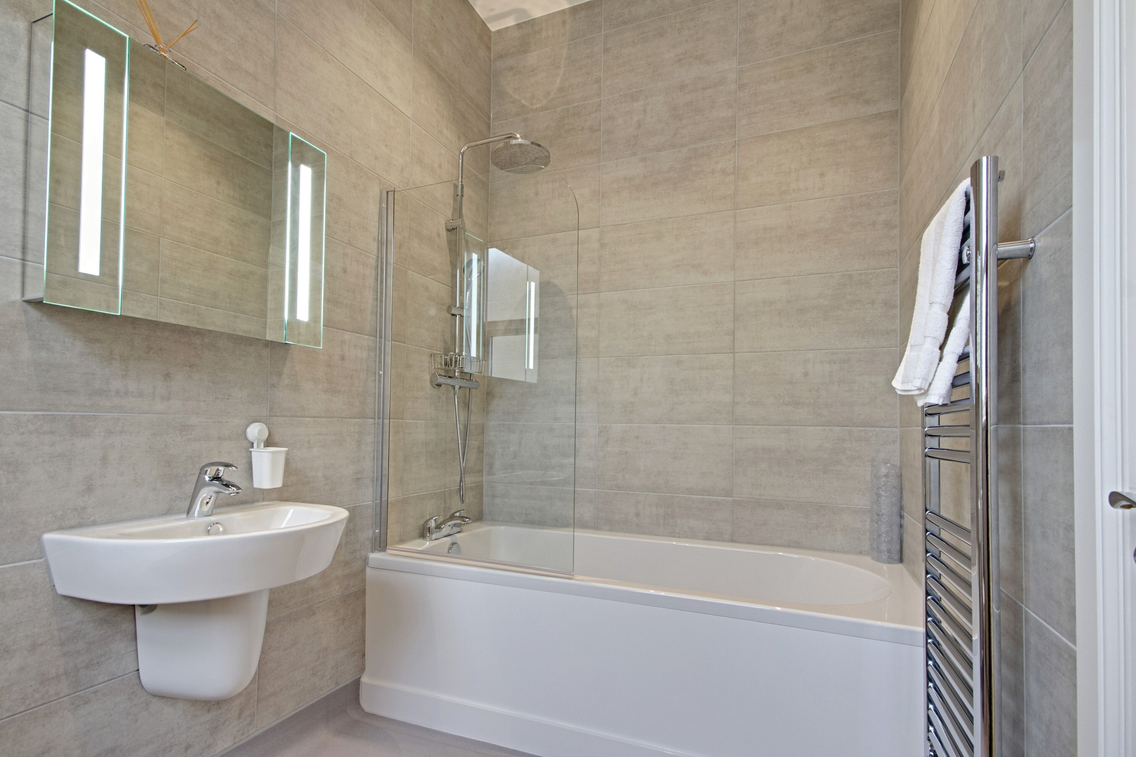 Un bany modern amb una banyera independent, un lavabo fixat a la paret i una dutxa amb envàs de vidre.