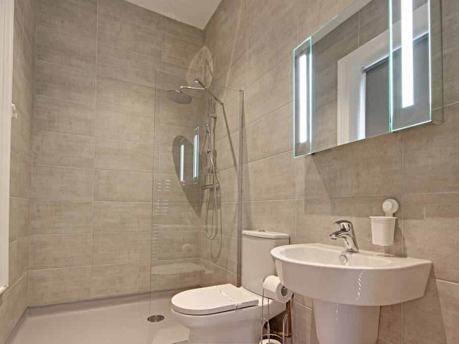 A modern bathroom with a shower, toilet, and sink.