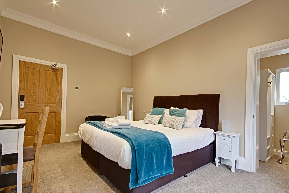 A bedroom with a bed, bedside tables, a chair, a desk, and a wardrobe.