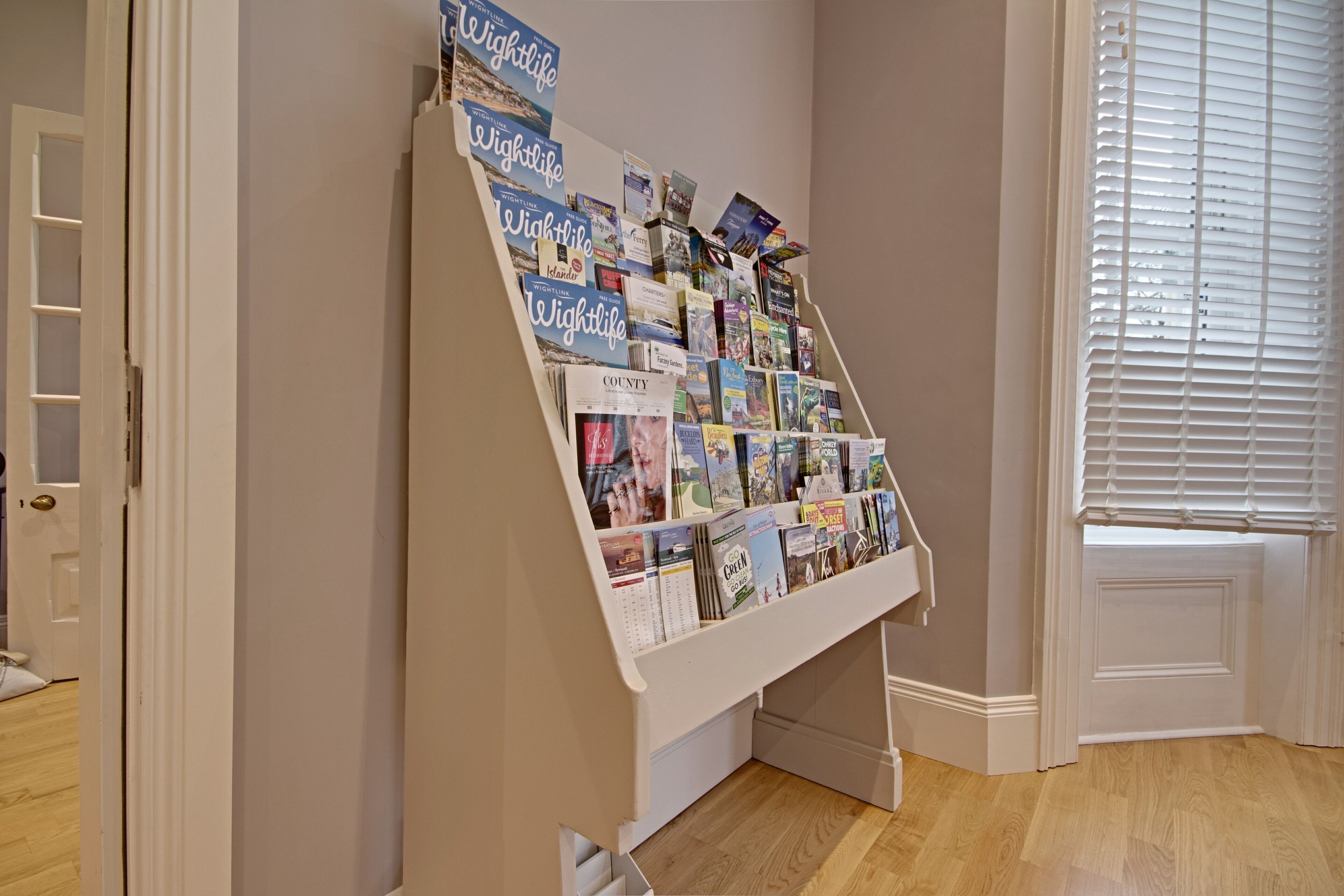A book display in a room with wooden flooring and a window with blinds.