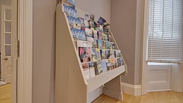 A book display in a room with wooden flooring and a window with blinds.