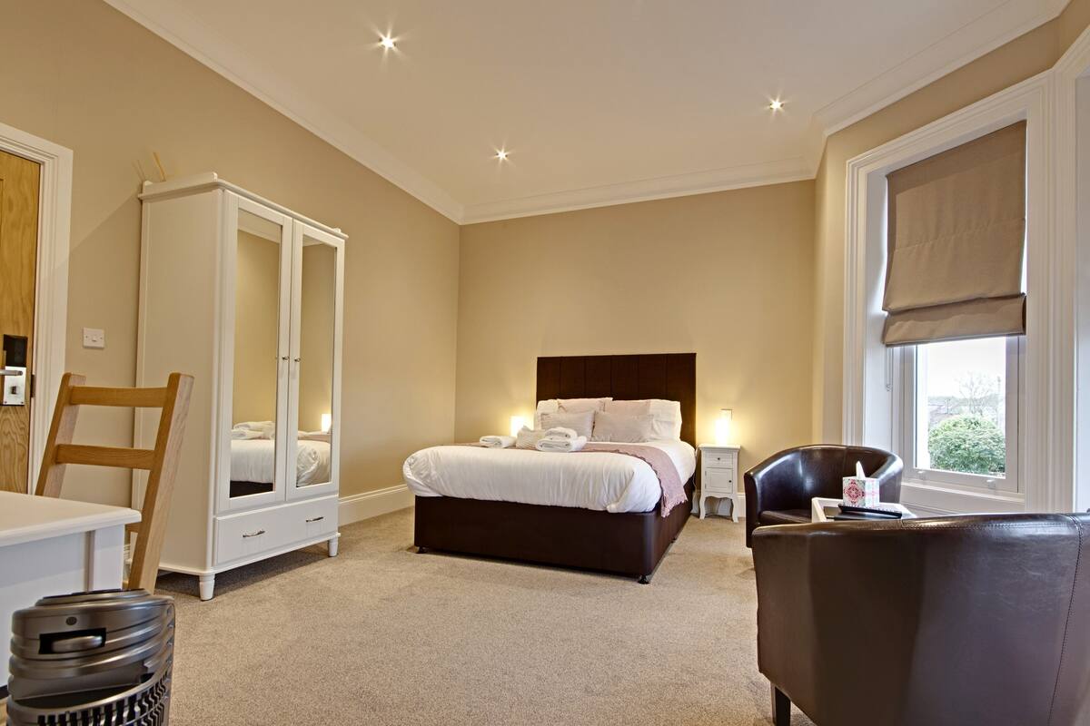 A bedroom with a bed, a wardrobe, a chair, and a bedside table.