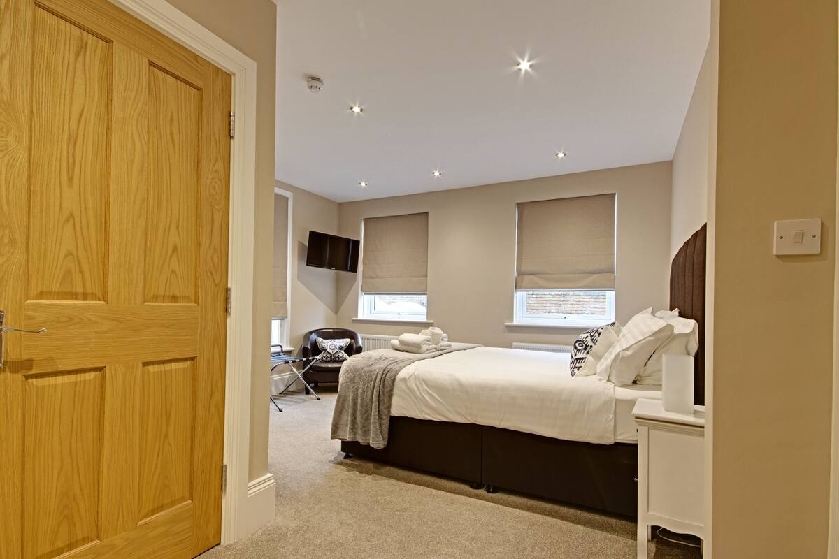 A bedroom with a bed, bedside table, and a television mounted on the wall.