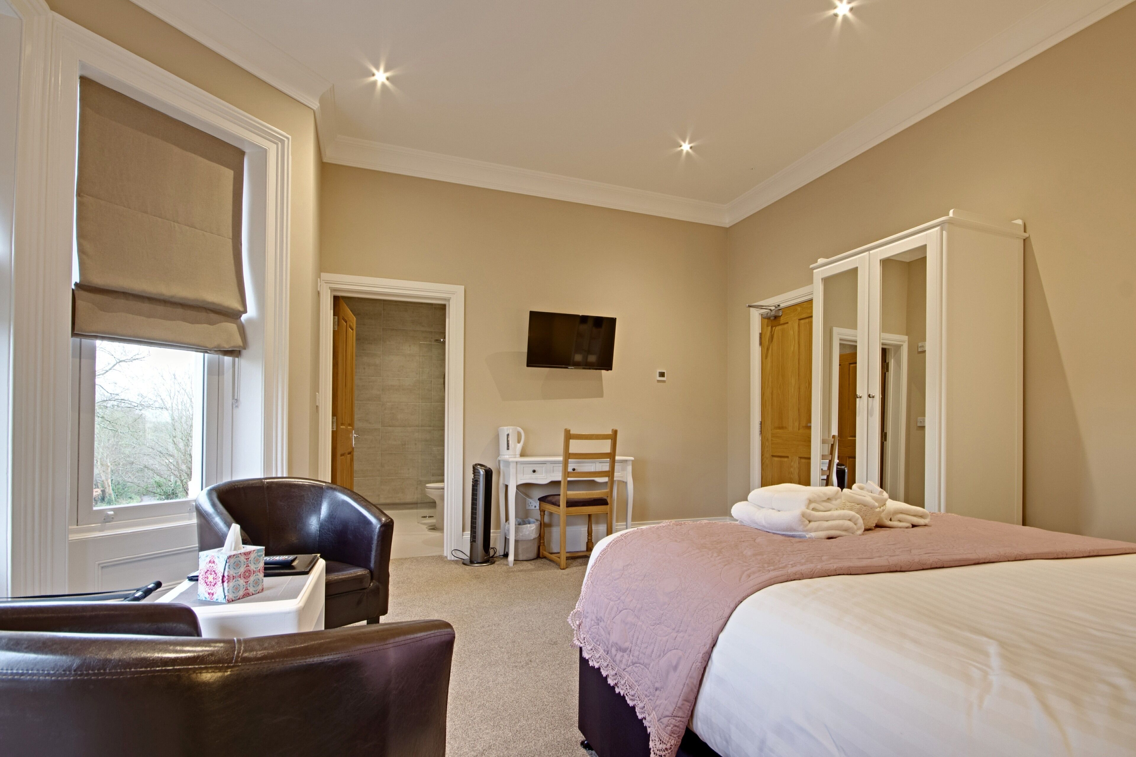 A hotel room with a bed, a desk, a chair, and a television.