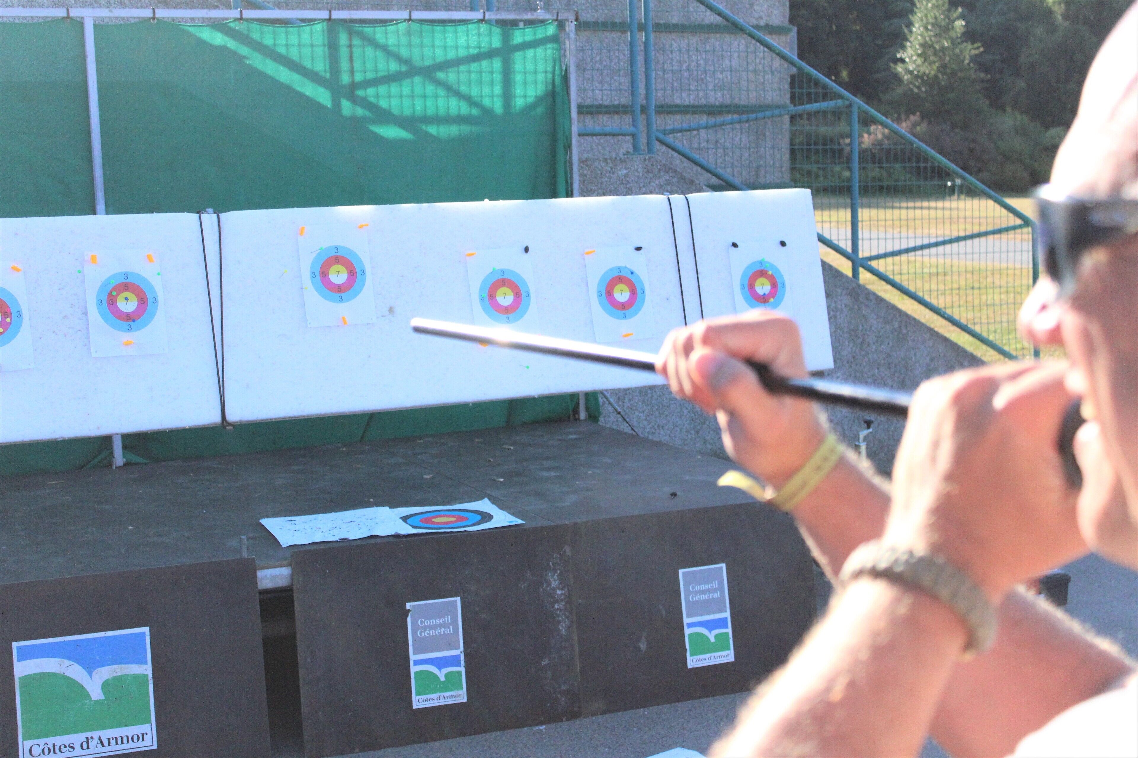 An archery range with multiple targets and a person aiming a bow.
