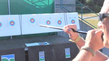 An archery range with multiple targets and a person aiming a bow.