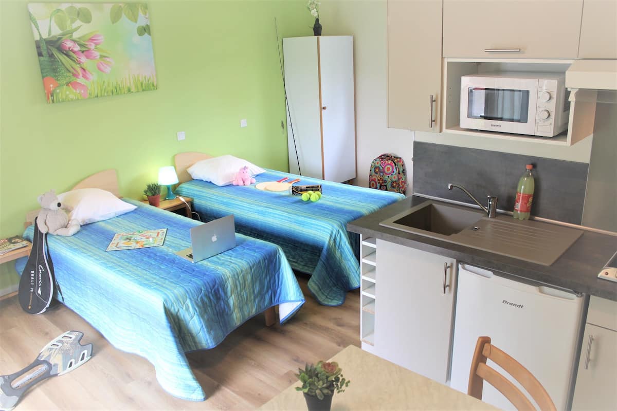 A room with two beds, a desk, a microwave, and a sink.