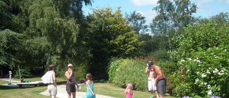 A group of people playing a game outdoors with cones and a garden in the background.