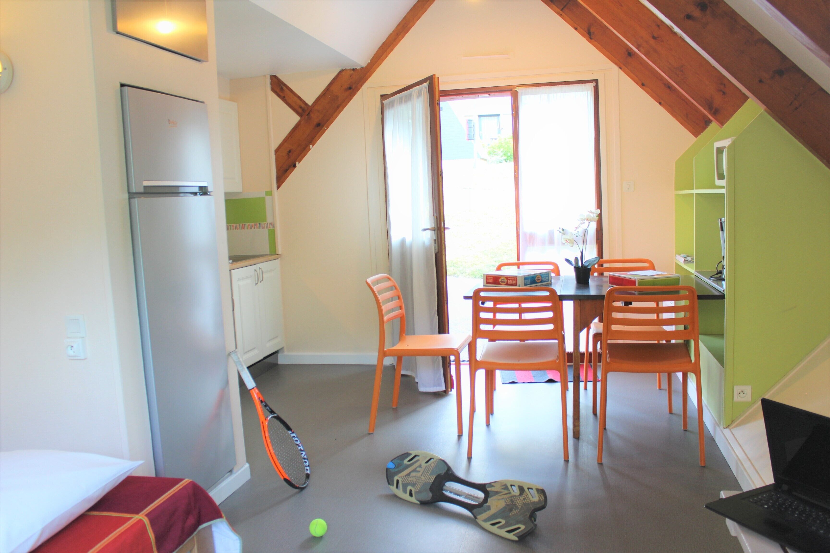 A compact kitchen with a refrigerator, dining table, and chairs.