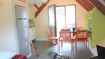 A compact kitchen with a refrigerator, dining table, and chairs.