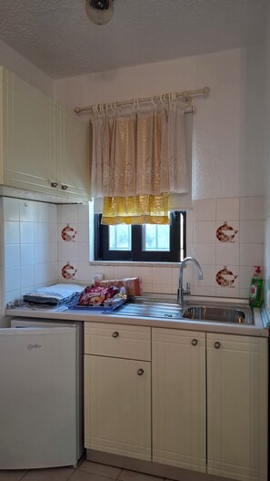 A kitchen with a window, a sink, and a refrigerator.