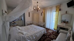A bedroom with a bed, a desk, a chair, a wardrobe, and a chandelier.